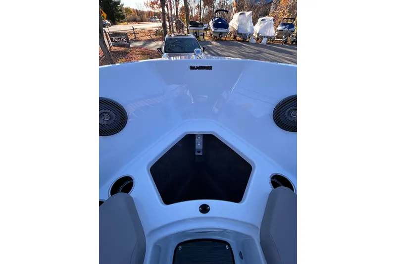 Slide: The Image of 2024 Glastron GX 215 boat interior with speakers and seating, parked outdoors. - 49
