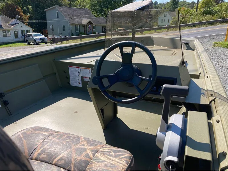 Slide: The Image of 2024 Lowe Roughneck RX1660 SC boat interior with steering wheel and camouflage seat. - 7