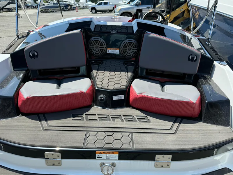 Slide: The Image of 2025 Scarab 165 ID boat interior with red and gray seating, speakers, and logo. - 15
