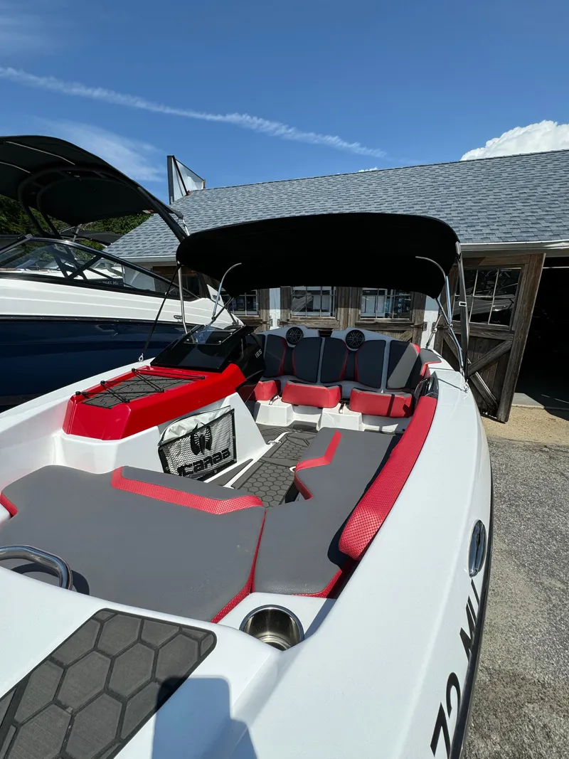 Slide: The Image of 2025 Scarab 165 ID boat with red and gray interior, docked under a canopy. - 18