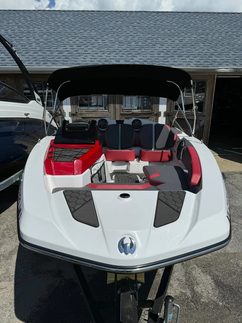 Slide: The Image of 2025 Scarab 165 ID boat with red and black seating, docked outdoors. - 3