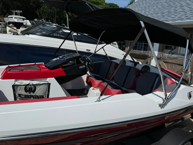 Slide: The Image of 2025 Scarab 165 ID boat with black canopy and red accents, docked outdoors. - 5