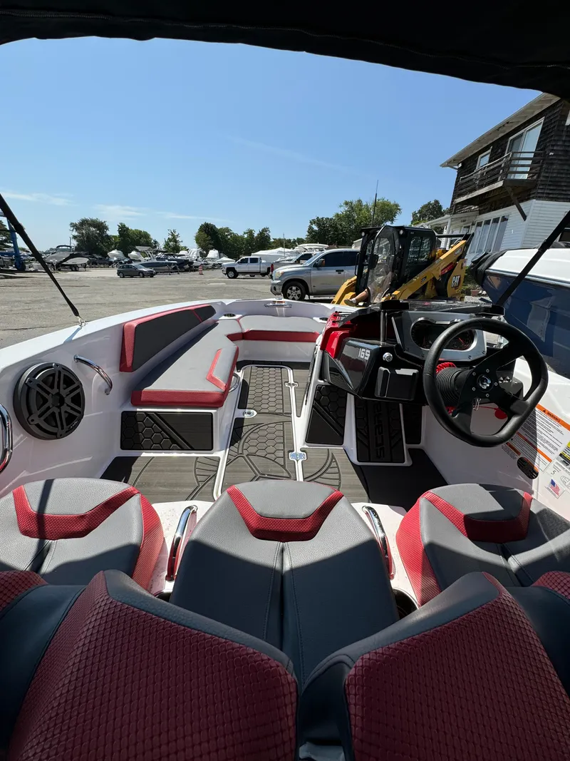 Slide: The Image of 2025 Scarab 165 ID boat interior with red and gray seating, steering wheel, and dashboard. - 8