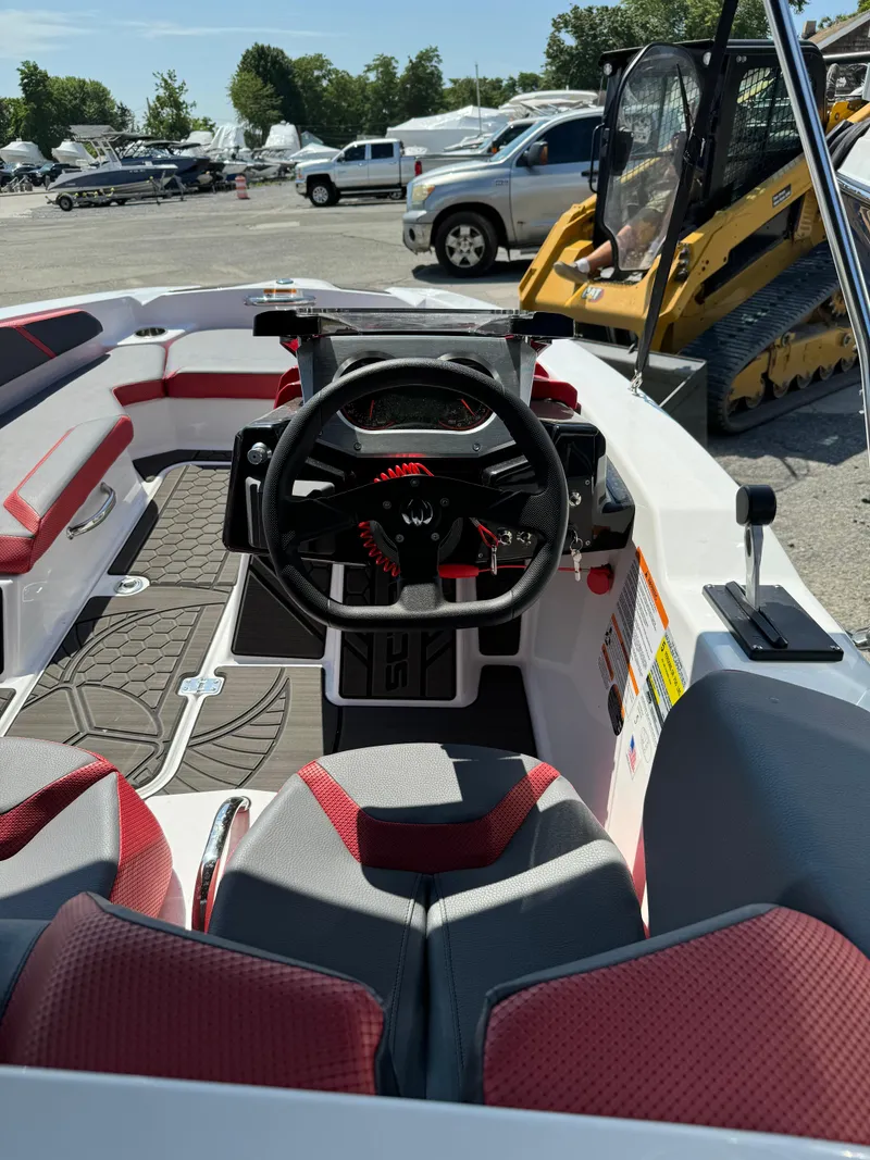 Slide: The Image of 2025 Scarab 165 ID boat interior with red and gray seating, steering wheel, and dashboard. - 9