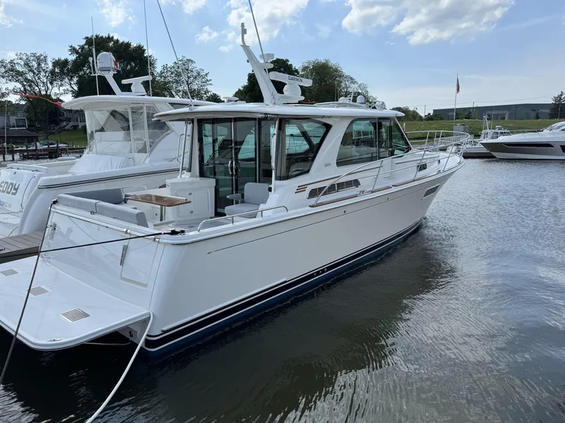 Slide: The Image of 2024 Sabre 43 Salon Express yacht docked in a marina under a partly cloudy sky. - 14