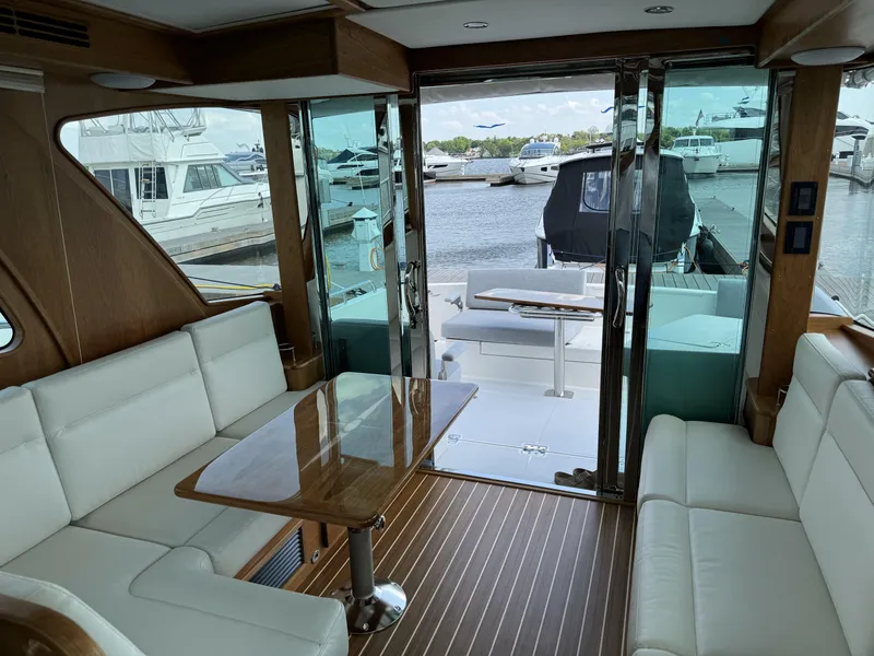 Slide: The Image of 2024 Sabre 43 Salon Express interior with white seating, wooden table, and marina view. - 20