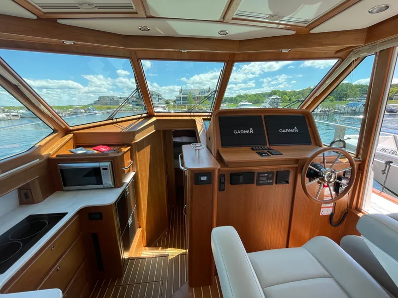 Slide: The Image of 2024 Sabre 43 Salon Express interior with helm, navigation screens, and kitchen area. - 26