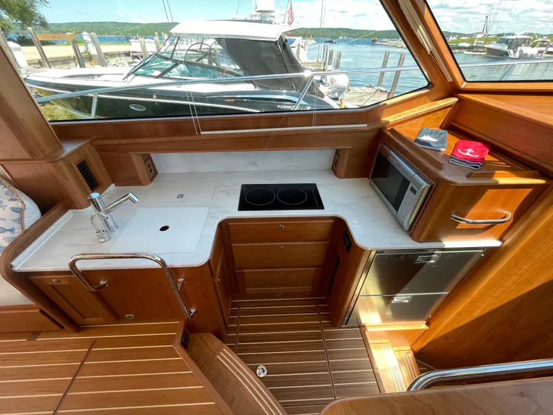 Slide: The Image of 2024 Sabre 43 Salon Express galley with modern appliances and wood finish, docked at marina. - 31