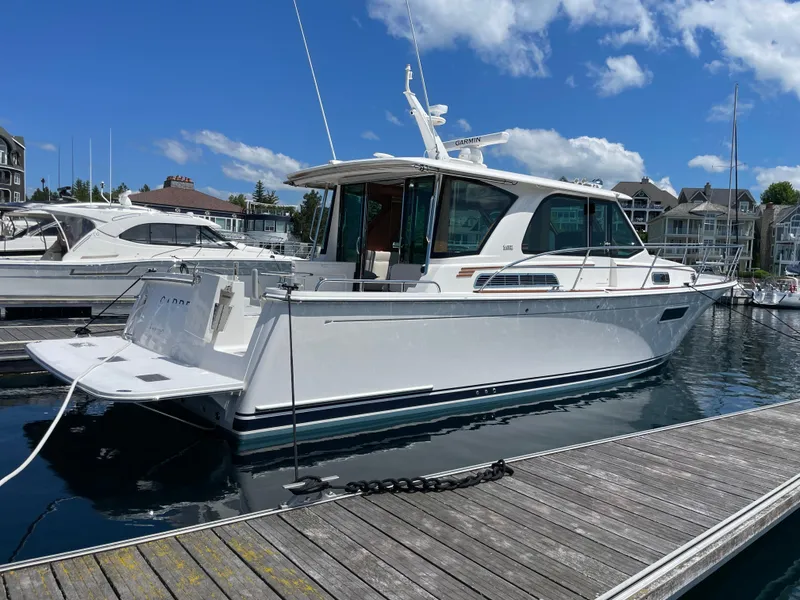 Slide: The Image of 2024 Sabre 43 Salon Express yacht docked at marina under blue sky. - 4