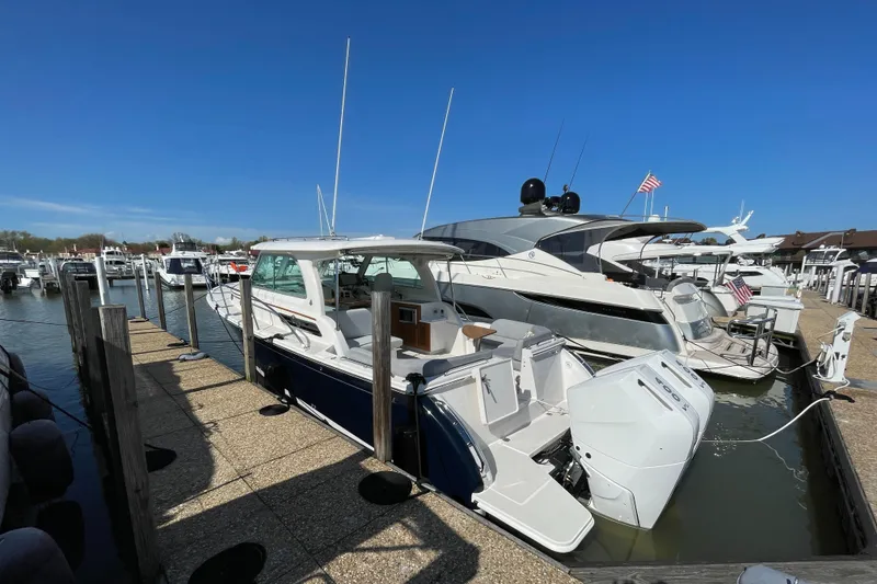 Slide: The Image of 2024 Back Cove 34O boat docked at marina under clear blue sky. - 12