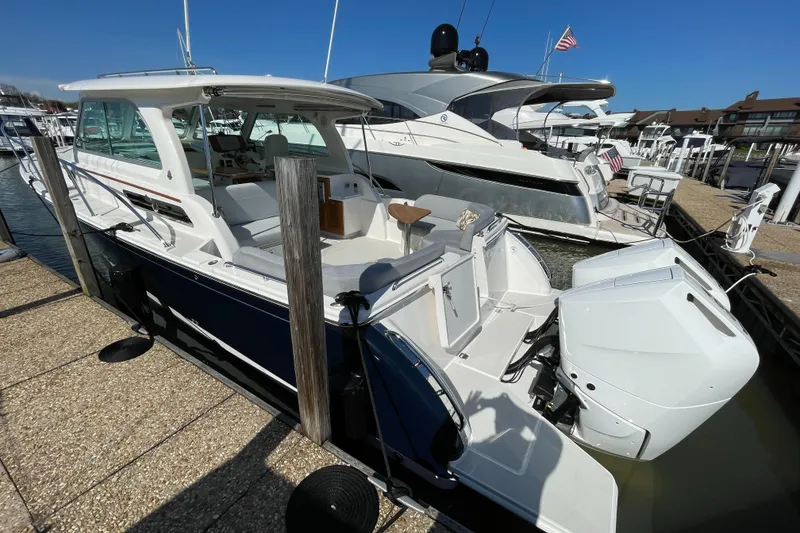 Slide: The Image of 2024 Back Cove 34O boat docked at marina, featuring sleek design and powerful outboard engine. - 14