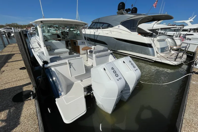 Slide: The Image of 2024 Back Cove 34O boat docked with dual outboard engines, sleek design, and spacious deck. - 15