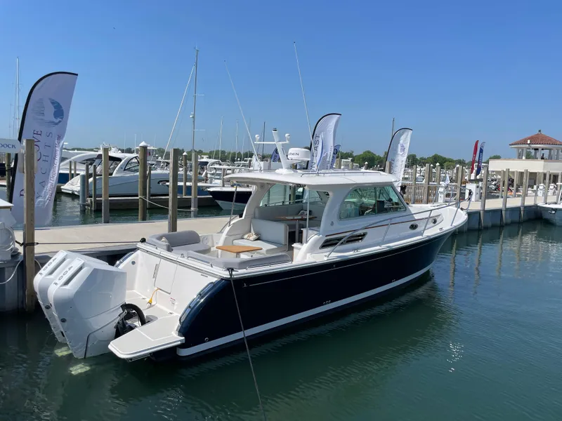 Slide: The Image of 2024 Back Cove 34O boat docked at a marina under clear blue skies. - 2