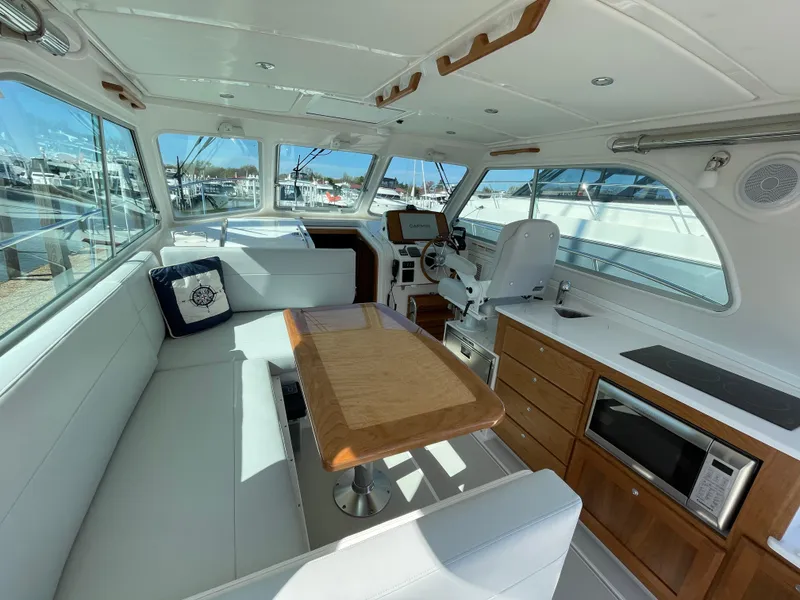 Slide: The Image of 2024 Back Cove 34O yacht interior with seating, helm, and kitchenette. - 20