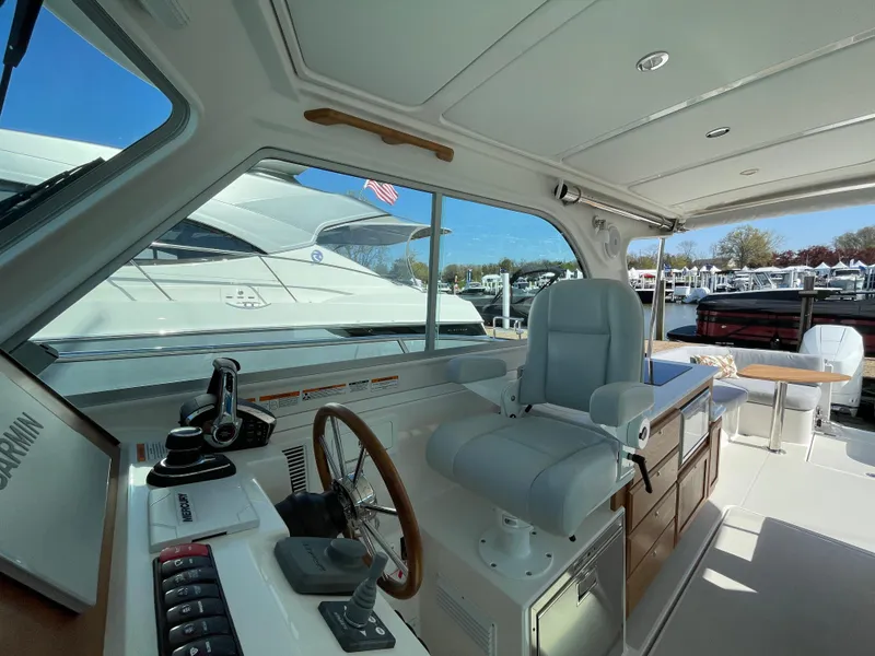 Slide: The Image of 2024 Back Cove 34O yacht interior with helm, seating, and marina view. - 28