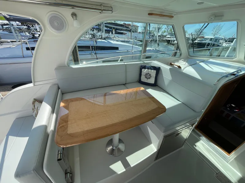 Slide: The Image of 2024 Back Cove 34O interior with elegant seating and wooden table, docked at marina. - 30