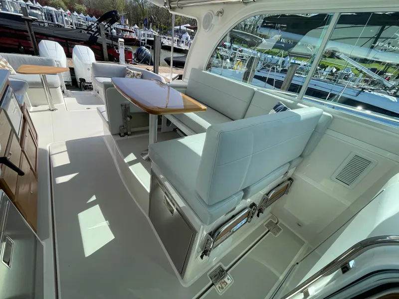Slide: The Image of 2024 Back Cove 34O yacht interior with elegant seating and dining area, docked at marina. - 33