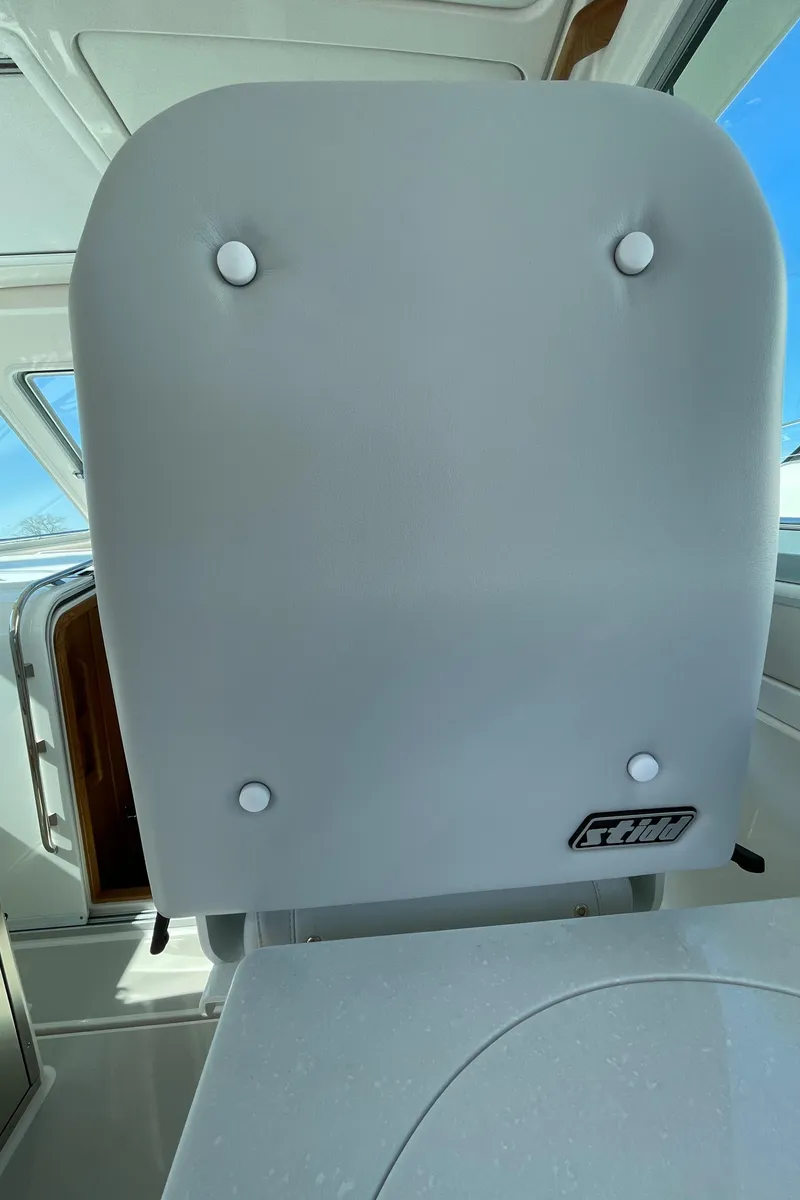 Slide: The Image of 2024 Back Cove 34O boat interior with cushioned seat and window view. - 35