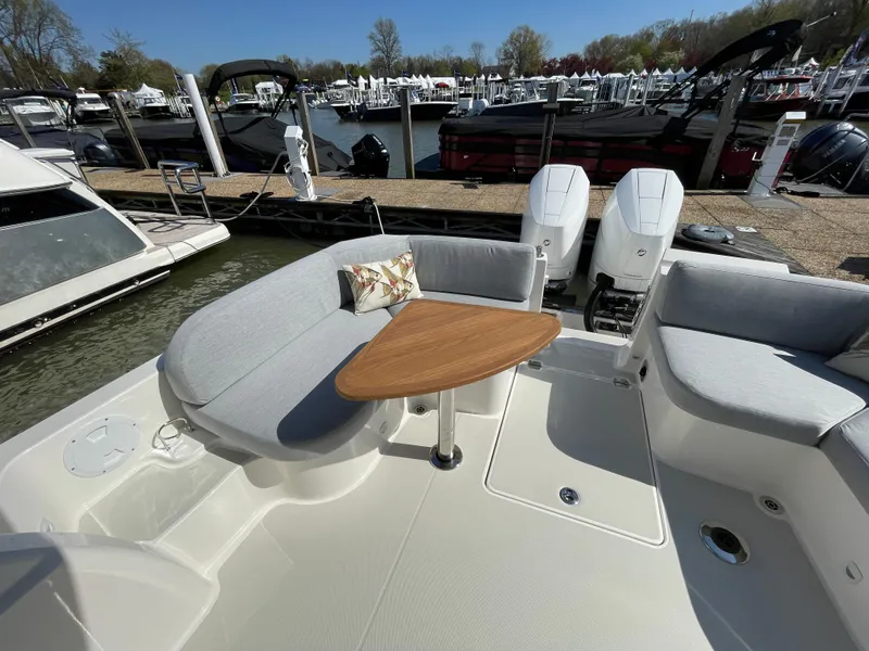 Slide: The Image of 2024 Back Cove 34O boat with cushioned seating and wooden table, docked at a marina. - 38