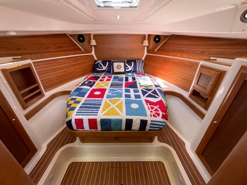 Slide: The Image of 2024 Back Cove 34O cabin with nautical-themed bedding and wooden interior. - 40