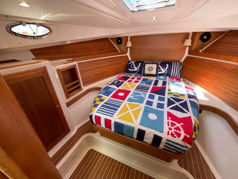 Slide: The Image of 2024 Back Cove 34O cabin with nautical-themed bedding and wooden interior. - 42