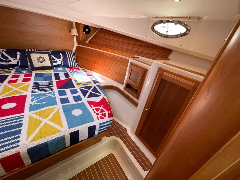 Slide: The Image of 2024 Back Cove 34O cabin with colorful nautical bedding and wooden interior. - 43