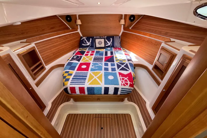 Slide: The Image of 2024 Back Cove 34O cabin with nautical-themed bedding and wooden interior. - 44