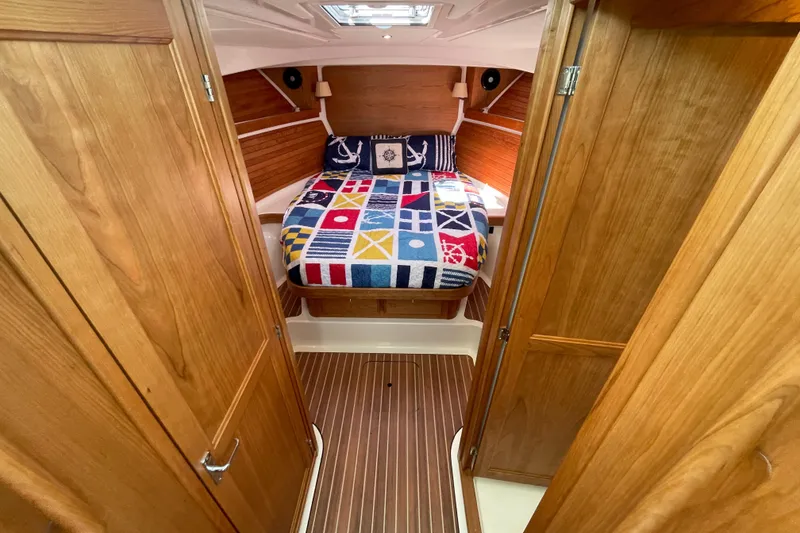 Slide: The Image of 2024 Back Cove 34O cabin interior with nautical-themed bedding and wooden finishes. - 45