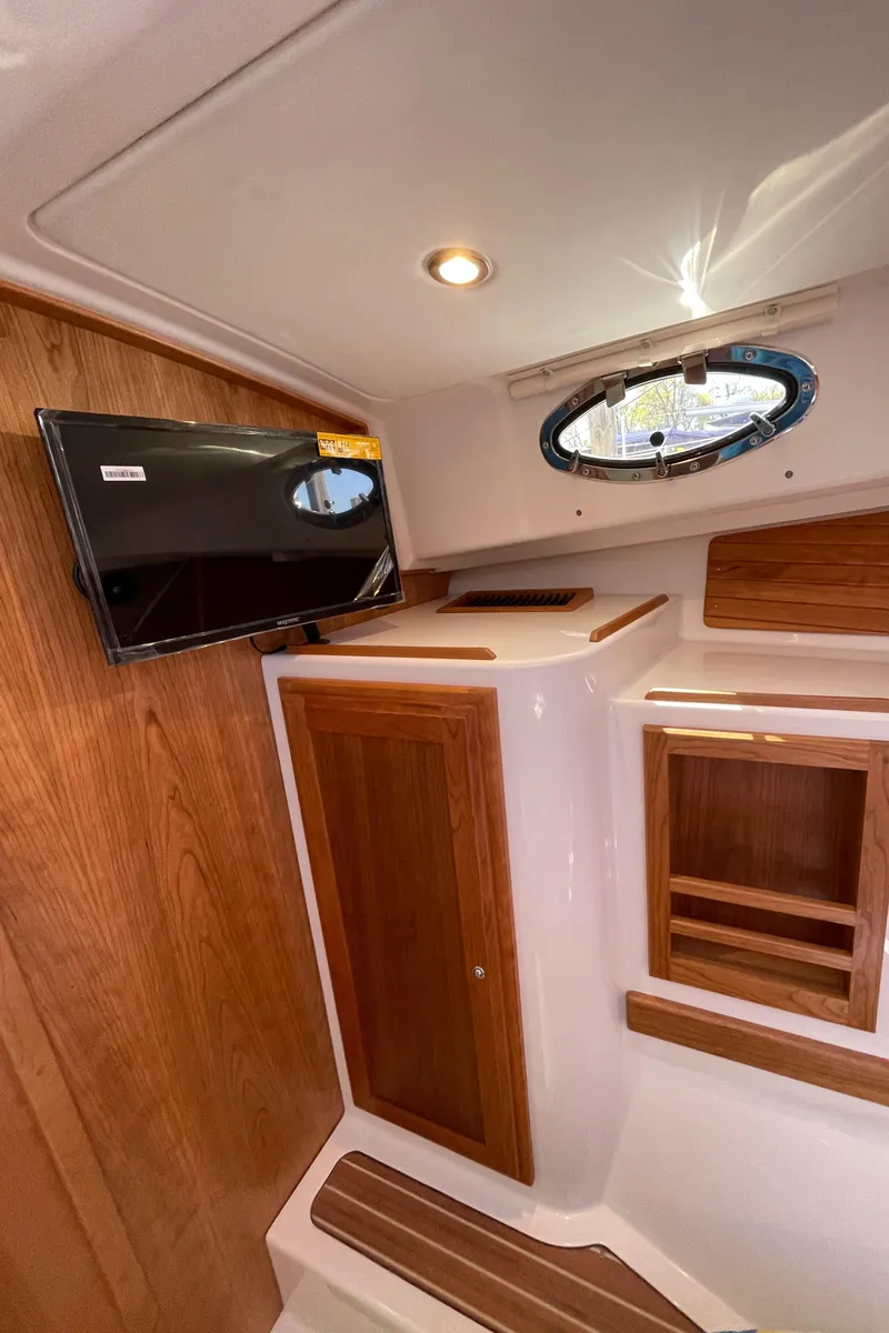 Slide: The Image of 2024 Back Cove 34O interior with wood paneling, TV, and porthole window. - 48