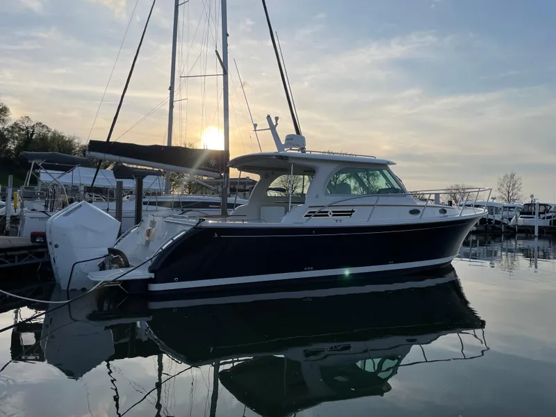 Slide: The Image of 2024 Back Cove 34O boat docked at sunset, reflecting on calm water. - 5