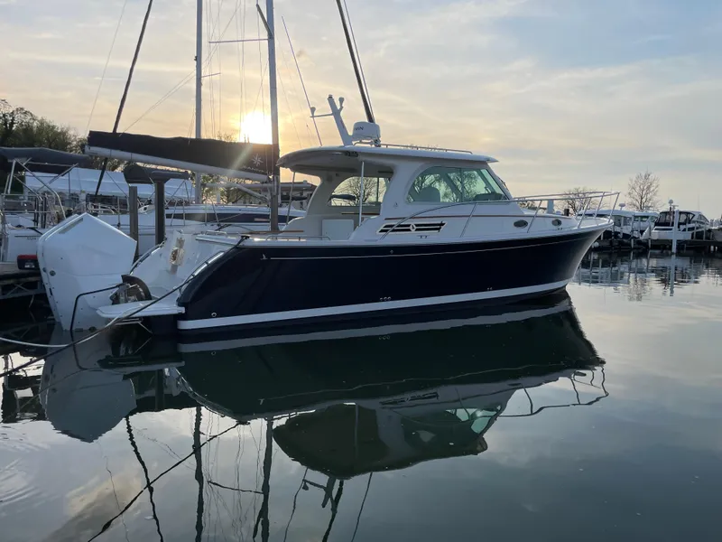 Slide: The Image of 2024 Back Cove 34O boat docked at sunset, reflecting on calm water. - 6