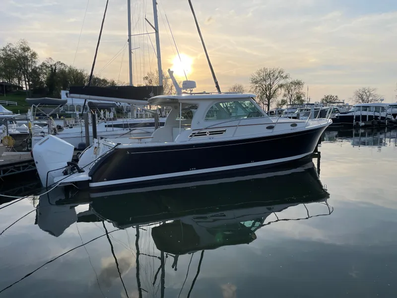 Slide: The Image of 2024 Back Cove 34O boat docked at sunset, reflecting on calm water. - 7