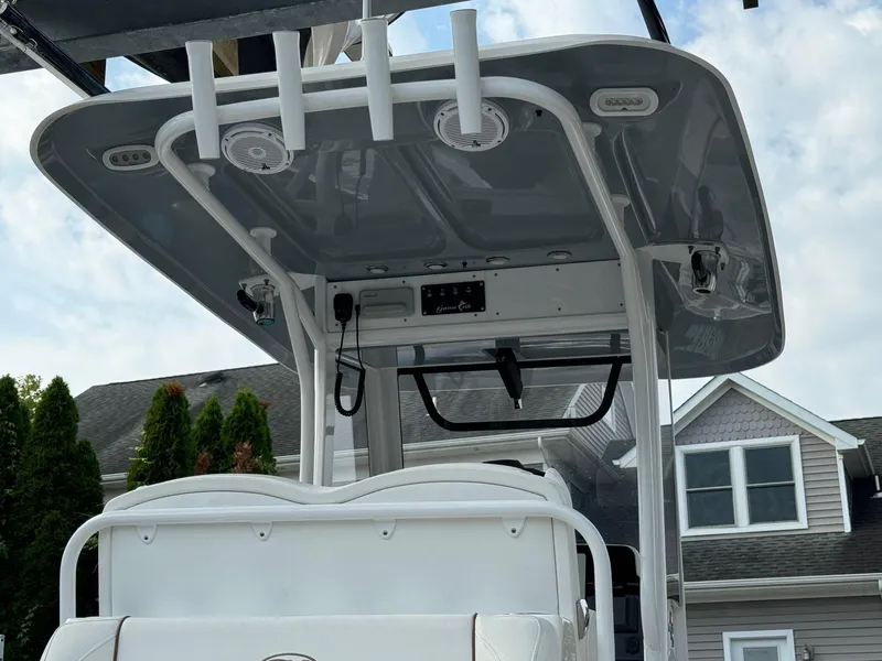 Slide: The Image of 2018 Sea Hunt Gamefish 27 boat with T-top and rod holders, docked near houses. - 10
