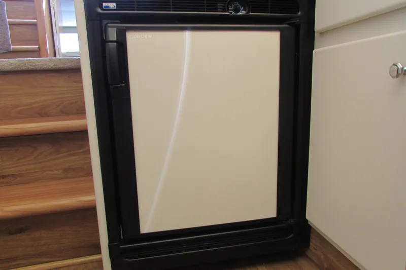 Slide: The Image of 1995 Carver 325 Aft Cabin interior with compact refrigerator near wooden stairs. - 12