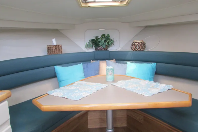 Slide: The Image of 1995 Carver 325 Aft Cabin interior with cozy seating, decorative pillows, and table setting. - 13