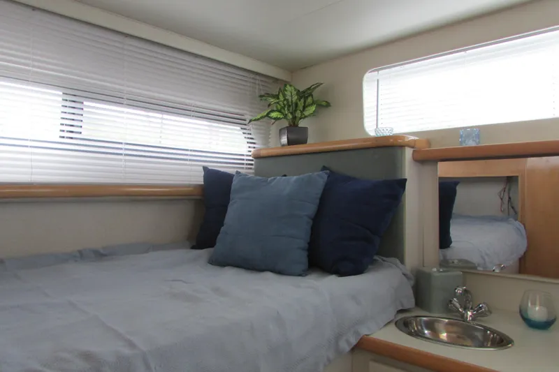 Slide: The Image of 1995 Carver 325 Aft Cabin interior with bed, pillows, sink, and potted plant. - 19