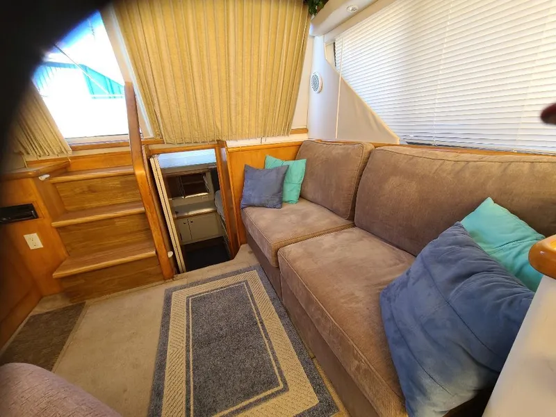 Slide: The Image of 1995 Carver 325 Aft Cabin interior with cozy seating, stairs, and decorative cushions. - 37