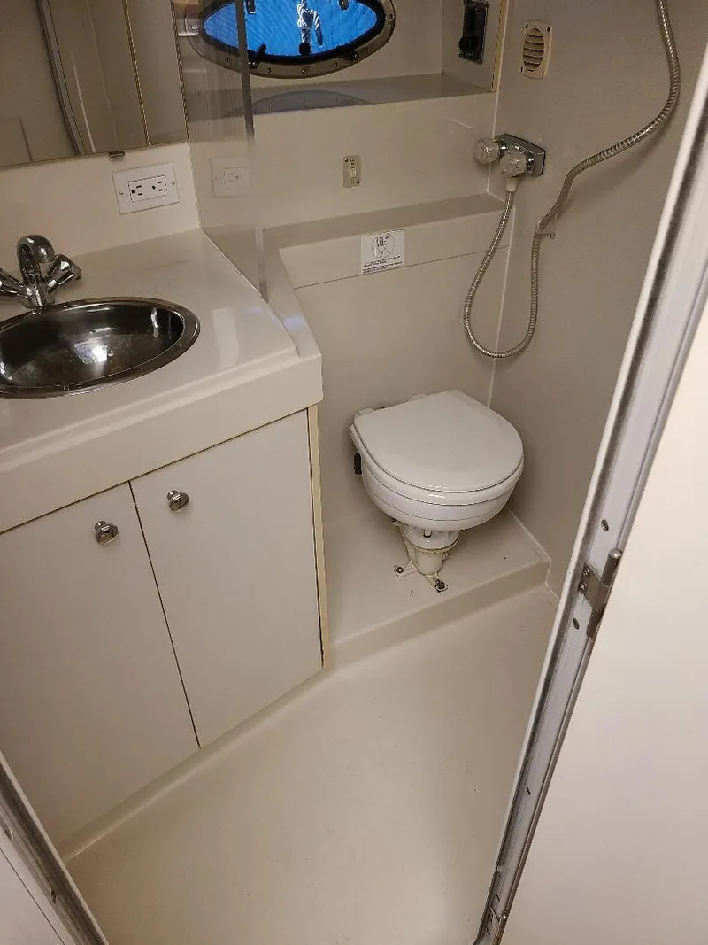 Slide: The Image of 1995 Carver 325 Aft Cabin bathroom with sink, toilet, and showerhead. - 40
