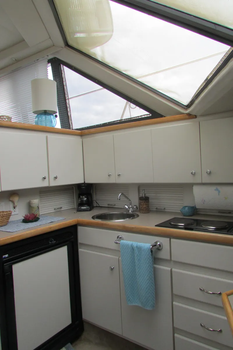 Slide: The Image of 1995 Carver 325 Aft Cabin kitchen with skylight, white cabinets, and modern appliances. - 9