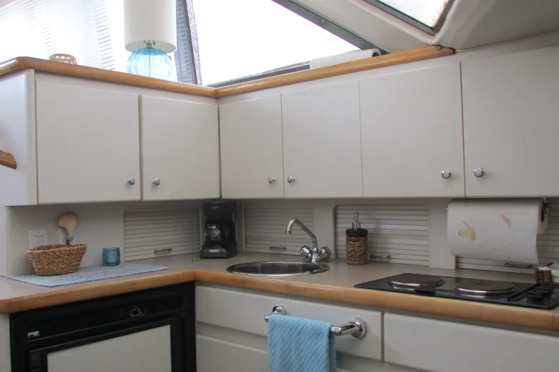 Slide: The Image of 1995 Carver 325 Aft Cabin kitchen with white cabinets, sink, and stove. - 10