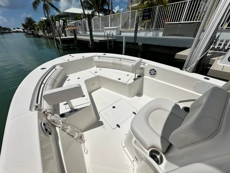 Slide: The Image of 2023 Sea Born LX24 boat interior with seating and cup holders, docked by a canal. - 13