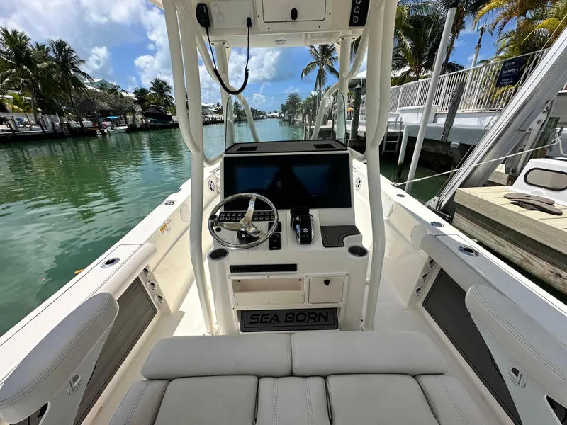 Slide: The Image of 2023 Sea Born LX24 boat interior with steering console, docked by a tropical canal. - 16