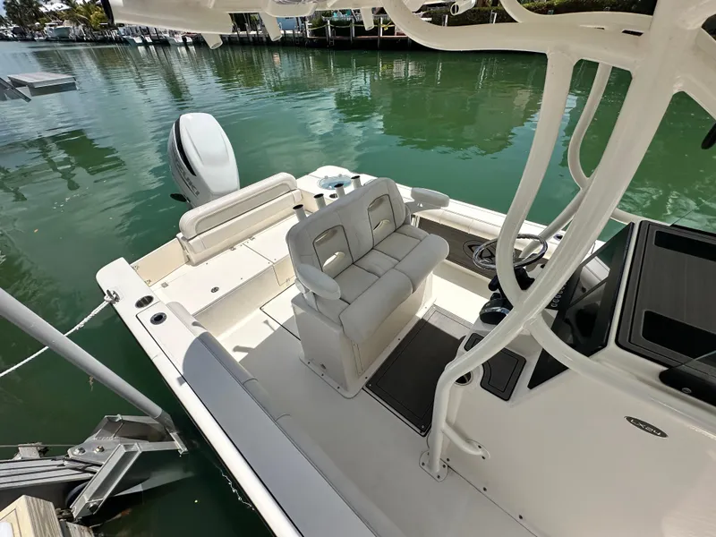 Slide: The Image of 2023 Sea Born LX24 boat interior with seating and steering, docked on calm water. - 17