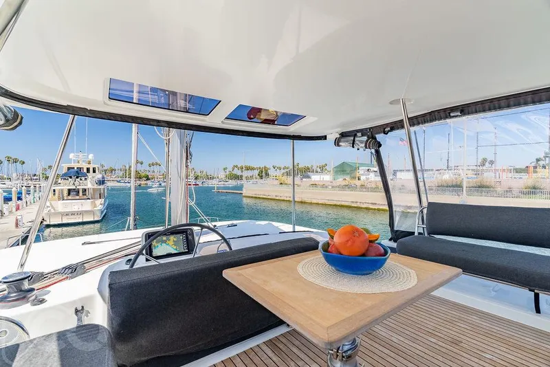 Slide: The Image of Lagoon 46 catamaran interior with seating, table, and fruit bowl, docked at marina, 2021 model. - 16