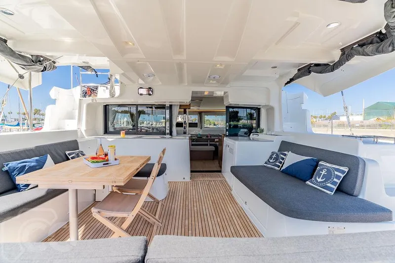 Slide: The Image of Spacious Lagoon 46 catamaran interior, featuring a dining area with wooden table and cushioned seating. - 25