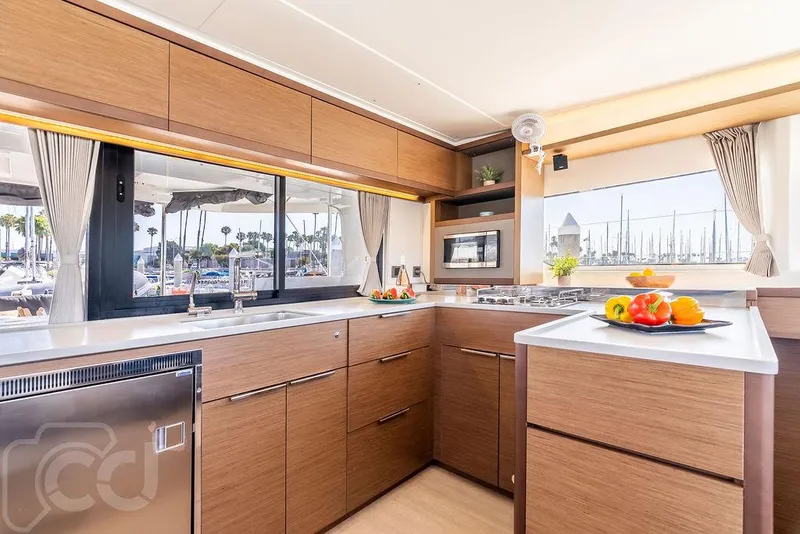 Slide: The Image of Modern kitchen interior of 2021 Lagoon 46 yacht with wood cabinetry and marina view. - 28
