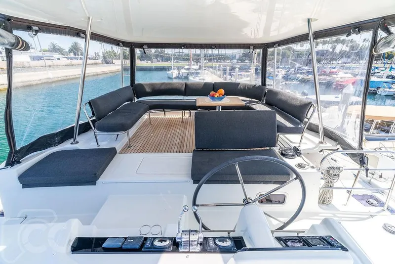 Slide: The Image of Luxurious 2021 Lagoon 46 yacht cockpit with seating, table, and steering wheel, docked at marina. - 29