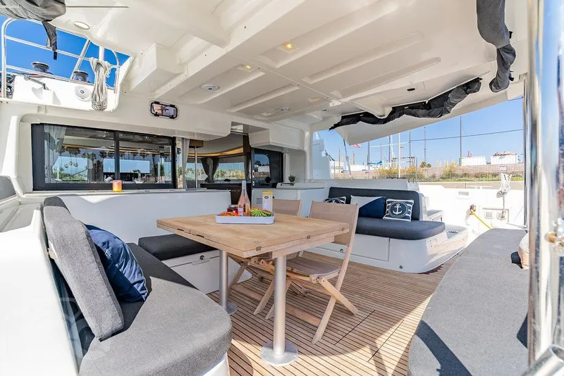 Slide: The Image of Spacious outdoor seating area on a 2021 Lagoon 46 catamaran with wooden table and cushions. - 42
