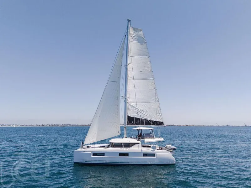 Slide: The Image of 2021 Lagoon 46 catamaran sailing on open sea under clear blue sky. - 8