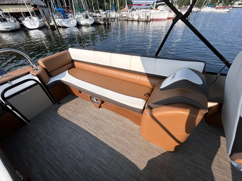 Slide: The Image of 2024 Avalon Catalina Quad Lounge boat interior with brown and white seating by the marina. - 11
